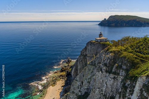 Принти на полотні Lighthouse standing on a steep rocky cliff in Primorye, with the vast Sea of Japan, rugged coastline, and blue horizon stretching behind it