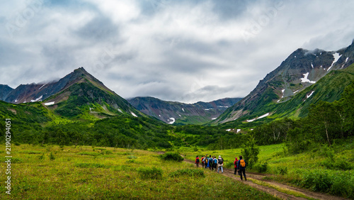 Foto Lush green valley in the Vachkazhets area of Kamchatka, surrounded by rounded volcanic hills, alpine meadows, dense vegetation, wildflowers, and soft mountain light