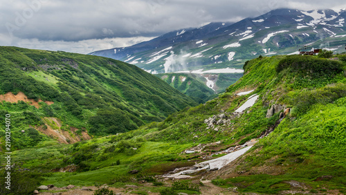 Obraz na płótnie Lush green valley in the Vachkazhets area of Kamchatka, surrounded by rounded volcanic hills, alpine meadows, dense vegetation, wildflowers, and soft mountain light