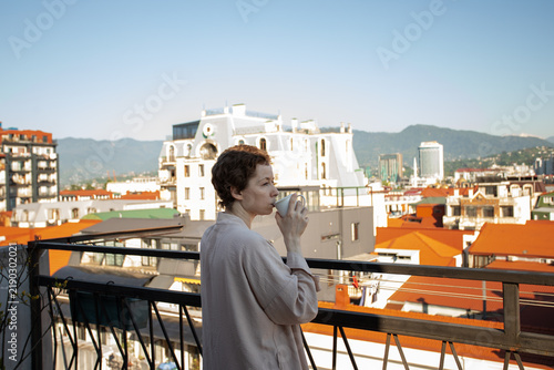 Foto cancer survivor sips a warm drink while standing on a terrace above the city, ex
