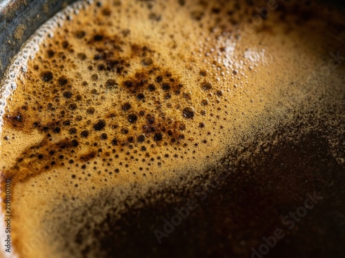 Close up of rich dark brown espresso crema with small bubbles in a ceramic cup