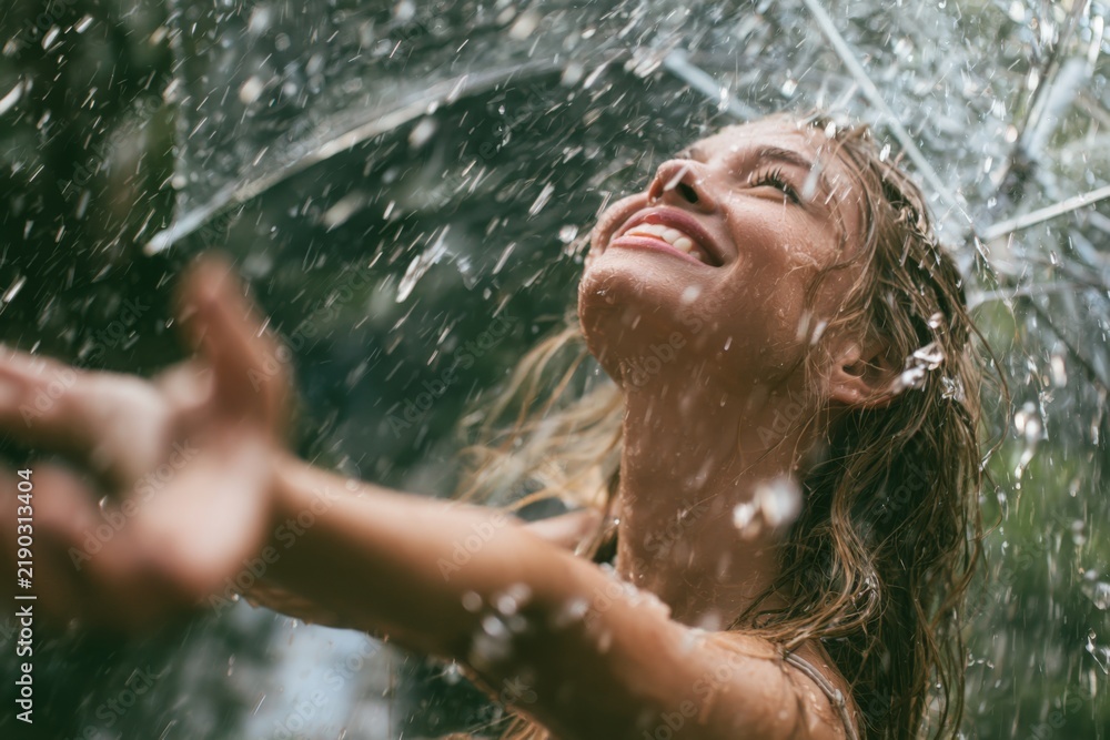 Fototapeta premium Woman smiles joyfully under rain shower