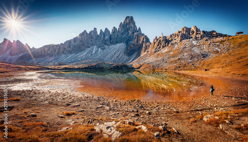 Photographer takes picture of Paterno peak. Stunning morning scene of Piani lake. Sunny autumn view of Dolomite Alps, Tre Cime Di Laveredo National Park, Italy, Europe. 