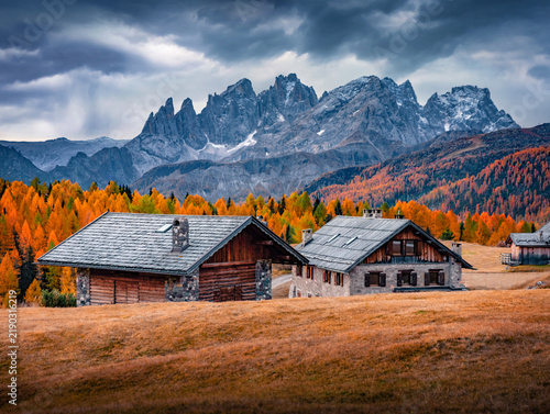 Breathtaking autumn view of wooden chalet on Fuchiade valley. Rainy morning scene of Dolomite Alps, Italy, Europe. Beauty of countryside concept background.
