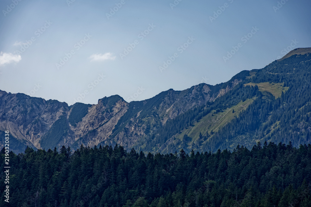 Fototapeta premium Mountain View Through Alpine Forest Framed by Dramatic Cloudy Sky Near Zugspitze