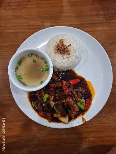 Fotografie Black pepper spicy chicken with white rice and soup on a white plate