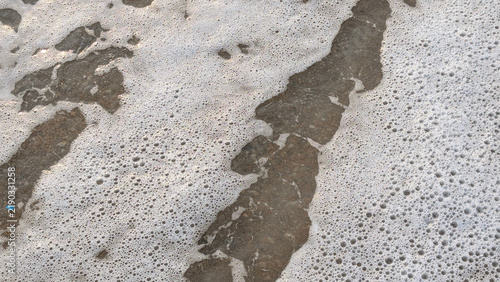 Принти на полотні Detailed texture of white sea foam bubbles spreading over dark wet sand and small pebbles