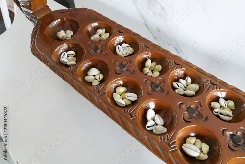 Bild auf Leinwand Mancala Carved Wooden Board Game with Cowrie Shells for Leisure Play