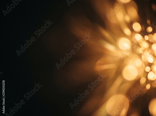 Luminous golden bokeh abstract background with warm glowing light streaks and dark shadows