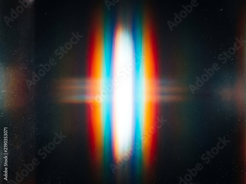 Vibrant chromatic aberration light leak with rainbow dispersion on dark grainy background