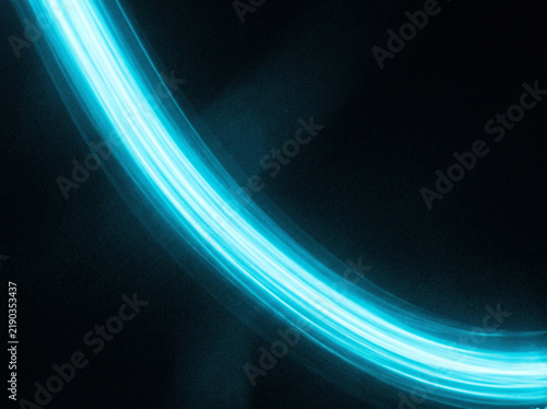 Vibrant blue light streak curving across dark background with motion blur and glow