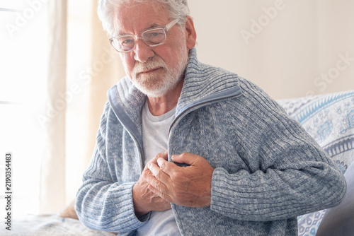Foto Senior man experiencing sudden chest pain, clutching his chest with both hands,