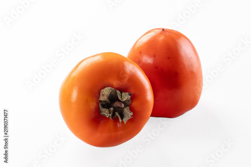 Obraz na plátne Two ripe orange persimmons with dried calyx on white background, smooth skin and