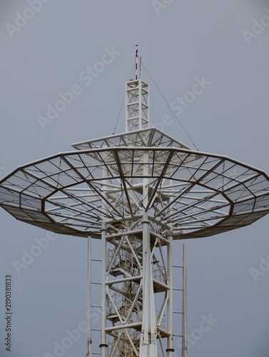 Foto Large industrial parabolic antenna tower viewed from below against a muted blue-