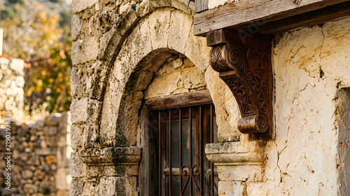 Ancient stone archway with a wooden corbel and iron window grate in a historic village