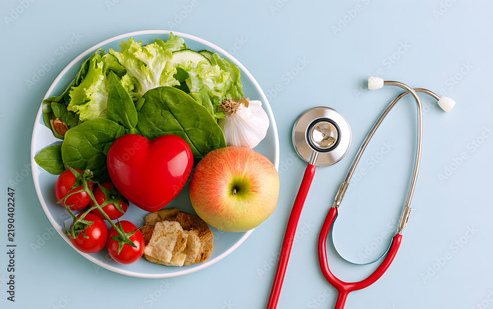 Obraz premium A top shot of a nutritious meal arrayed on a plate features a stethoscope and a red heart symbolizing a cholesterol diet and diabetes management against a soft pastel blue backdrop. It encapsulates th