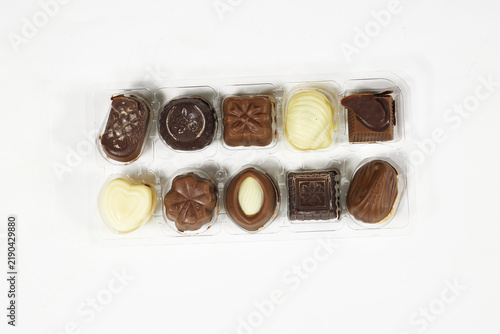 Фотография Assorted Chocolate Pralines in Clear Plastic Tray on White Background — Gourmet