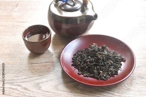 dry Chinese tea leaves with pottery pot and glass on table