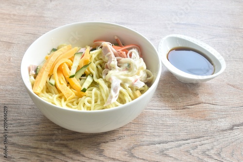 Hiyashi Chuka boiled cold ramen yellow Japanese noodles topping ham and vegetable dressing mayonnaise on bowl dipping soy sauce