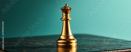Plakat Gold queen chess piece standing proudly on a dark textured surface against a turquoise background