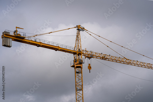 Obraz na płótnie Low angle view of a yellow tower crane against a dramatic overcast sky