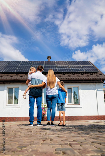 happy family on the background of a house with solar panels on the roof