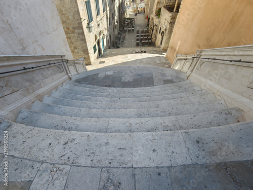 Grand stone staircase ascending toward a historic building under a clear blue sky symbolizing ambition and journey.