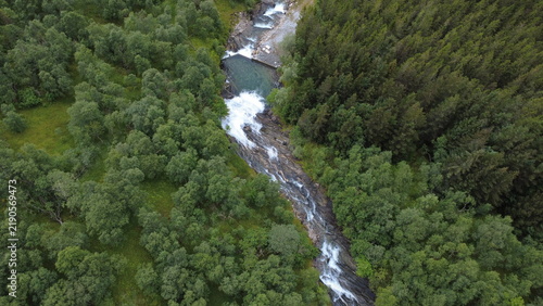 Bild auf Leinwand Overhead drone view of a mountain stream and waterfall with a clear pool flowing through mixed forest canopy