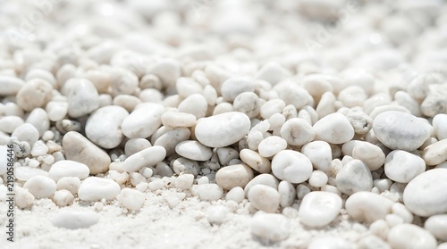 Smooth white pebbles resting on bright sandy beach under sunlight