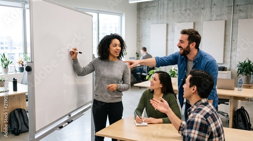 Diverse team collaborating enthusiastically around a whiteboard in a modern office setting