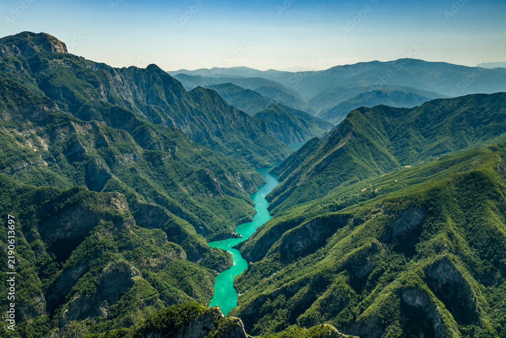 Obraz premium Turquoise Waterway Winding Through a Forested Mountain Canyon at Komani Lake