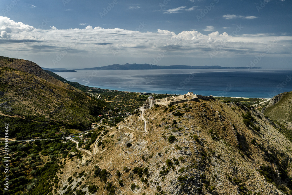 Fototapeta premium Borsh Fortress Above a Coastal Bay, Oblique Aerial View of Historic Stone Walls and Distant Mountains
