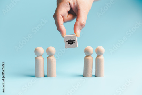 фотографія Education selection concept with hand choosing graduation symbol above wooden people, representing student admission, scholarship, academic opportunity, recruitment and future learning