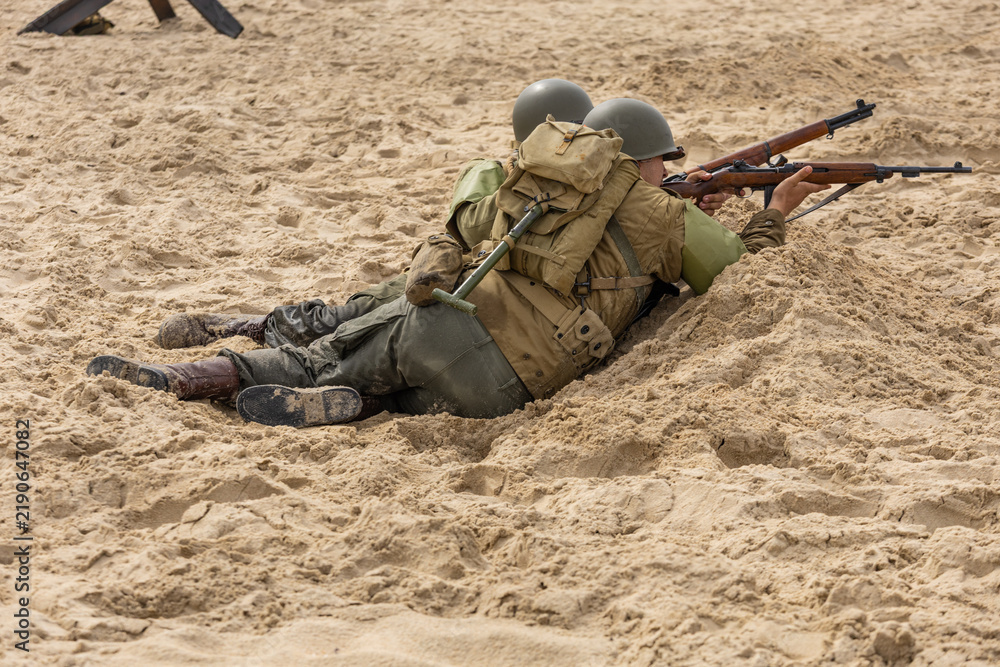Obraz premium Historical reconstruction. An American infantry soldiers from the World War II fight on the beach. 