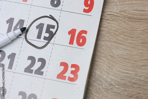 Paper calendar on the table with the number 15 circled.
