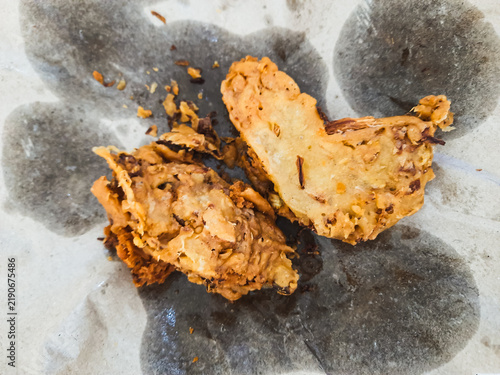 Indonesian vegetable fritters known as bakwan or bala-bala, made from battered vegetables and deep fried until crispy, served on absorbent paper as a popular traditional street food snack.