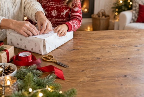 Family Preparing Gifts at Home: Hands Wrapping a Present on a Wooden Table