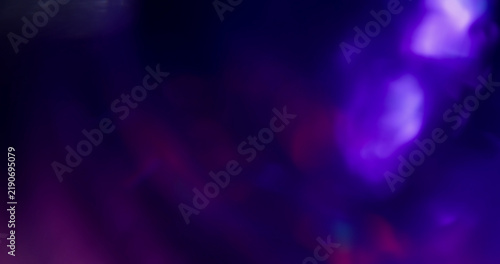 Defocused glow. Color light flare. Blur blue purple pink optical texture illuminated glint on art neon kaleidoscope bokeh dark black background.