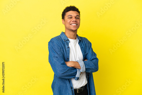 Foto Young African American man isolated on yellow background with arms crossed and l