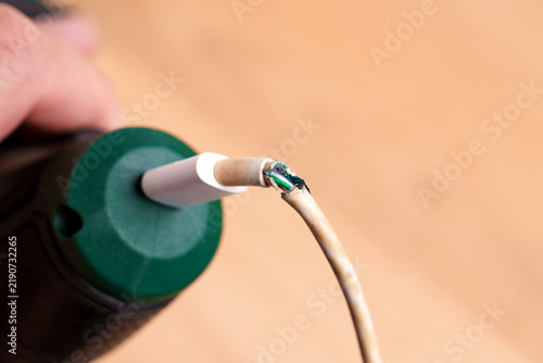 Damaged charging cable plugged into green cordless screwdriver close up