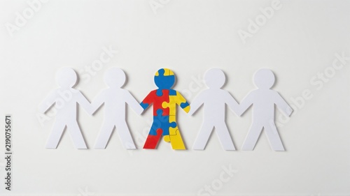 Paper chain of figures with one highlighted as a colorful puzzle piece representing inclusion