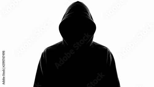 Dark silhouette of an unrecognizable person wearing a hoodie isolated on white background.
