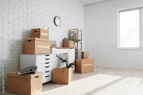 Chests of drawers with cardboard boxes near white brick wall in office on mov...