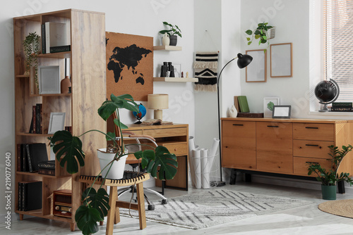 Interior of travelers office with workplace, shelf unit and plants