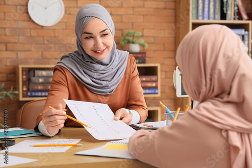Muslim mother with her little daughter learning Arabic language at home