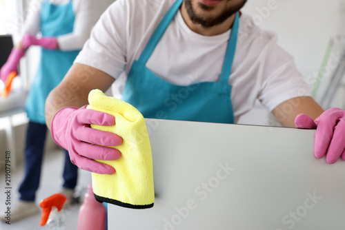 Male janitor cleaning computer monitor in office, closeup