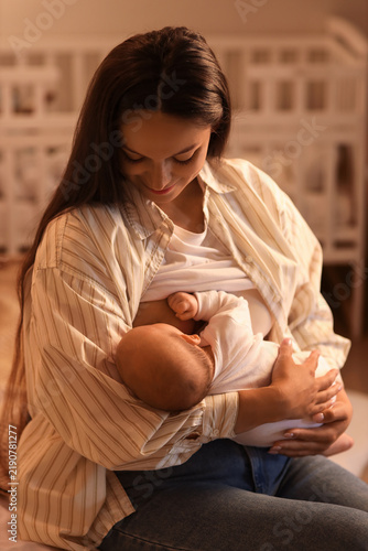 Mother breastfeeding her baby in bedroom at night