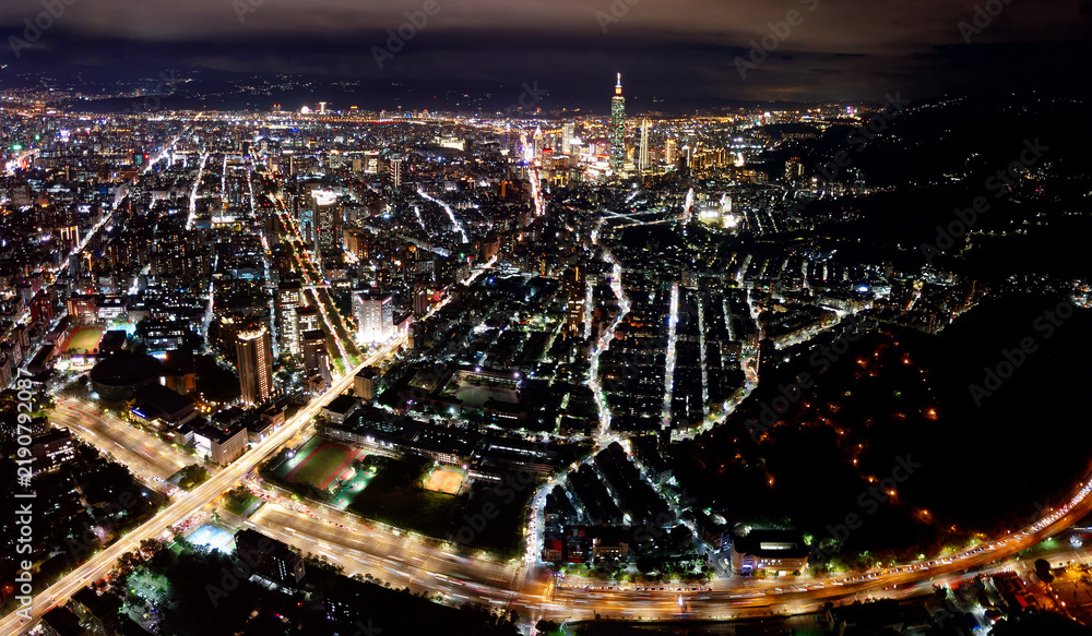 Obraz premium Aerial panorama of Taipei at night, vibrant capital city of Taiwan, with 101 Tower standing amid high-rise buildings in Xinyi Downtown and city lights of the crisscrossing streets dazzling in the dark