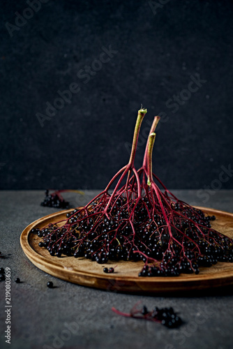 Fresh organic elderberry bunches on a rustic wooden tray