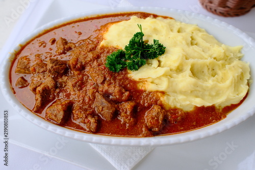 Foto Serbian goulash with mashed potatoes and fresh parsley garnish close-up